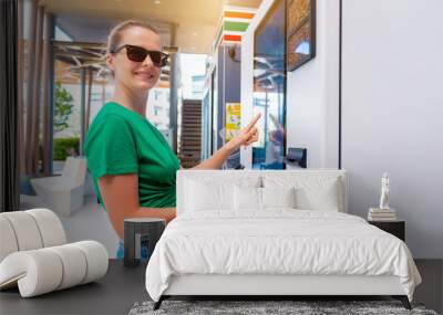 Young woman paying for coffee at vending machine using contactless method of payment  Wall mural