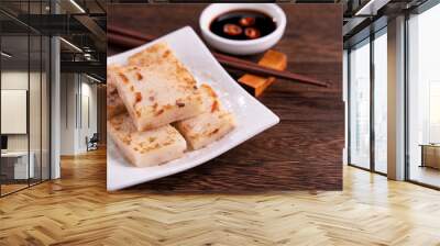 Delicious turnip cake, Chinese traditional local dish radish cake in restaurant with soy sauce and chopsticks, close up, copy space. Wall mural