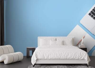 Girl write on open white book or accounting on a minimal clean light blue desk with laptop and accessories, copy space, flat lay, top view, mock up Wall mural