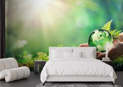 hands holding globe glass in green forest - environment concept Wall mural