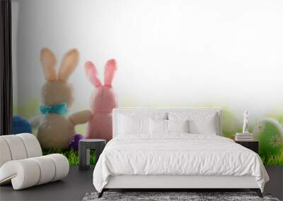 two bunnies with decorated eggs isolated on sunny meadow Wall mural