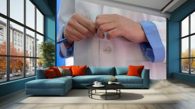 Female doctor hands with pan. A woman in a white lab coat with blue cuffs. Wall mural