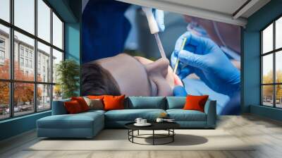 Teenager in dentistry. A dentist and an assistant treat the teeth of a young man. Wall mural