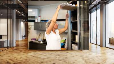 A young woman puts donuts in a showcase,stock photo Wall mural