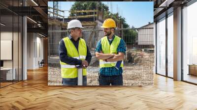 Man in hardhat and green jacket posing on building site Wall mural