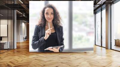 A young female manager in smart casual dress stands with confident to express ambitious target of her business strategy. Young female executive with tablet in her hand shows  positive gesture Wall mural