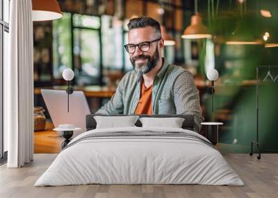 Man working on laptop, freelancer with computer in cafe at table, man in glasses smiling looking in camera. Model by AI generative Wall mural