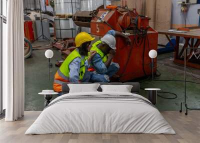 Mechanical engineers from two cultures in safety cloths working together to inspect the machines and production systems in a metal factory. Cooperation of two engineers from 2 ethnicities. Partnership Wall mural