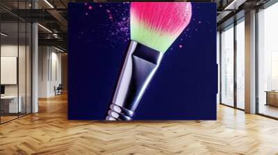 A vibrant, colorful makeup brush with a gradient tip against a dark background, showcasing artistic splashes of color. Wall mural