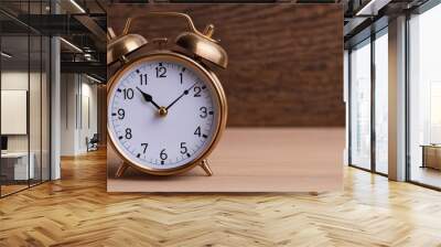 A vintage gold alarm clock rests on a wooden surface, showcasing its classic design and detailing against a natural backdrop. Wall mural