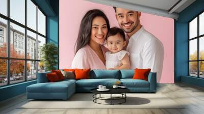 A happy family portrait featuring a mother, father, and baby against a soft pink background, radiating love and joy. Wall mural