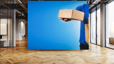 delivery service man holding cardboard boxes on blue background copy space Wall mural