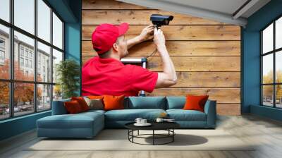 home security - man installing outdoor surveillance camera on wooden wall copy space Wall mural