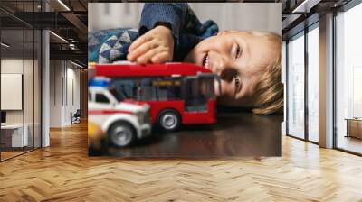 little boy playing with toy cars on the floor at home Wall mural