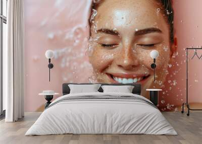 skin care and hydration concept. smiling woman with eyes closed and water splash around the face on light pink background Wall mural