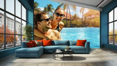 smiling happy couple having fun together in resort swimming pool. summer vacation, getaway travel. banner with copy space Wall mural