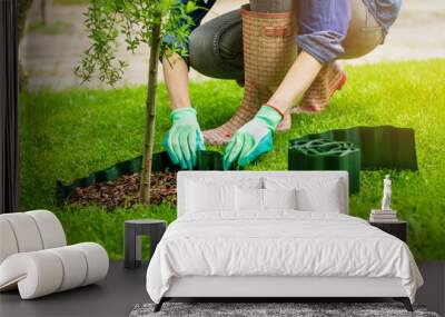 woman install plastic lawn edging around the tree in garden Wall mural