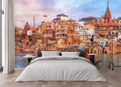 Ancient Varanasi city architecture at sunset with view of sadhu baba enjoying a boat ride on river Ganges. Wall mural