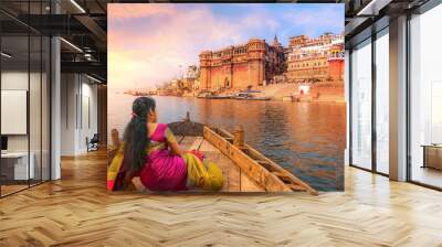 Ancient Varanasi city architecture with Ganges river bank. Indian female tourist enjoy boat ride on the river Ganges at sunset Wall mural