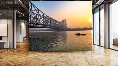 Historic Howrah bridge at Kolkata with view of fishing boat on river Ganges at sunrise  Wall mural