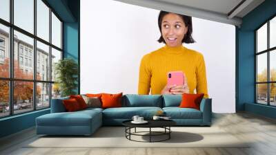 Copyspace photo of Young hispanic girl with short hair wearing casual yellow sweater isolated over white background stupor with something occurring in social media Wall mural