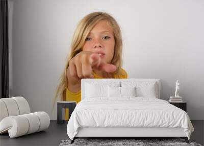 Young blonde kid girl wearing yellow dress over white background pointing displeased and frustrated to the camera, angry and furious ready to fight with you. Wall mural