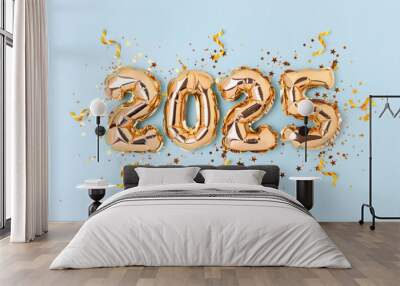 2025 New Year holidays concept. Golden inflatable balloons, ribbons and glittering stars confetti on a blue background. Wall mural