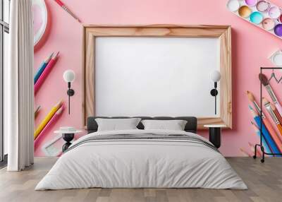 Painter workplace wooden blank photo frame white stationery palette pencils on soft pink background Wall mural