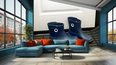 Pairs of blue rubber boots standing in hallway near door. Wall mural