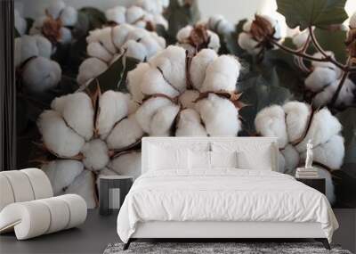 Close-up of multiple soft white cotton blossoms with green leaves on a white background, highlighting the natural beauty of cotton plants Wall mural