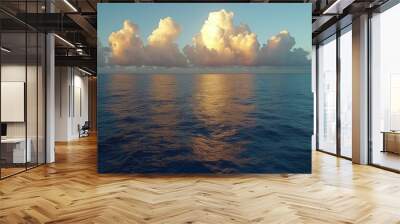 Serene ocean landscape with fluffy white clouds reflected on the calm sea at dusk, symbolizing tranquility and the beauty of marine nature Wall mural