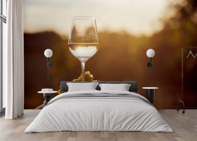 Glass of white wine with grape at sunset Wall mural