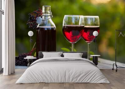 Glasses of elderberry wine and elderberries on wooden table Wall mural