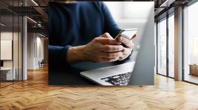 man with mobile phone and laptop in office Wall mural