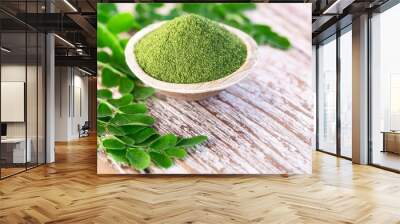 Moringa powder in coconut bowl with original fresh Moringa leaves on wooden background Wall mural