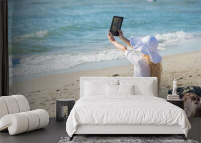 Young woman with tablet on the seaside in sunny day Wall mural