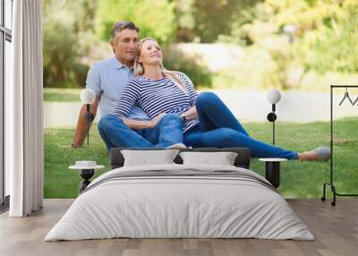 Mature couple, smile and relax on grass for healthy marriage, love relationship and bonding in park. Happy man, woman and sitting on lawn for support, care and romantic time together in nature garden Wall mural