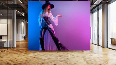 a girl in a witch costume for Halloween with a broom and a pumpkin in neon light Wall mural