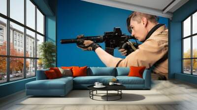 a male special agent soldier in a bulletproof vest with an automatic rifle on a blue background Wall mural