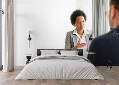 Businesswomen talking to client in her office. African American HR manager sitting at desk in office talking with a potential new employee during job interview. Copy space Wall mural