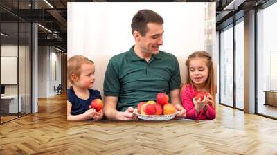 A young dad with two little children spend time at home.  The concept of family values.  Life style.  The modern role of men in the family. Wall mural