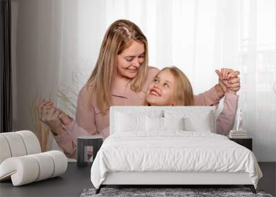 Shot of a happy cheerful mom hugging her little daughter with love by the window at home Wall mural