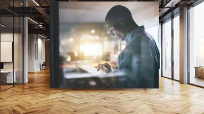 Anything is doable with dedication. Cropped shot of a handsome young businessman using a digital tablet during a late night in a modern office. Wall mural