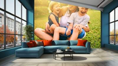 Filling their days with laughter and fun. Shot of a mother bonding with her two adorable little children outdoors. Wall mural