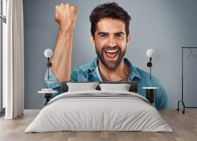 Happy man, fist and celebration for winning, success or victory against a grey studio background. Excited portrait of male person or winner in achievement, win or accomplishment on mockup space Wall mural