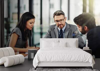 Its a meeting of the minds. Shot of three colleagues sitting around a meeting tablet in the office. Wall mural