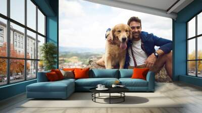 The view is great from up here. Cropped portrait of a handsome young man and his dog taking a break during a hike in the mountains. Wall mural