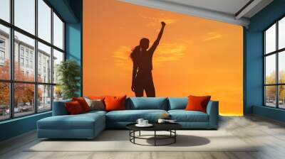 Empowered woman raising arm in celebration at sunset Wall mural