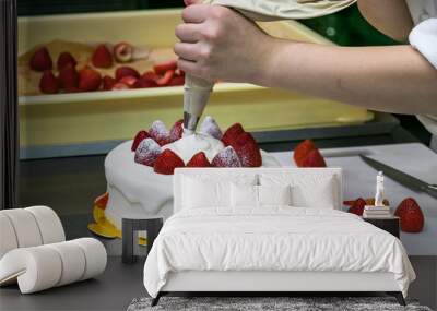 Female pastry chef hands, decorating a strawberries cake with a cream sleeve. Wall mural