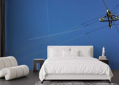 electric streetlamp hanging on cable before blue summer sunny sky with jet contrails Wall mural